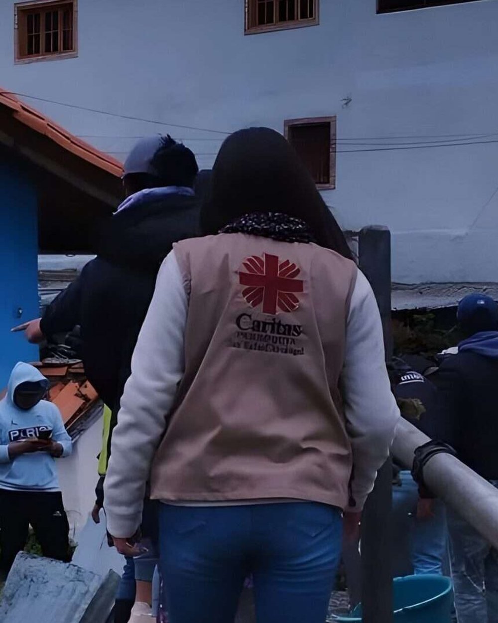 Voluntaria de Cáritas Parroquial en labor comunitaria, logo visible